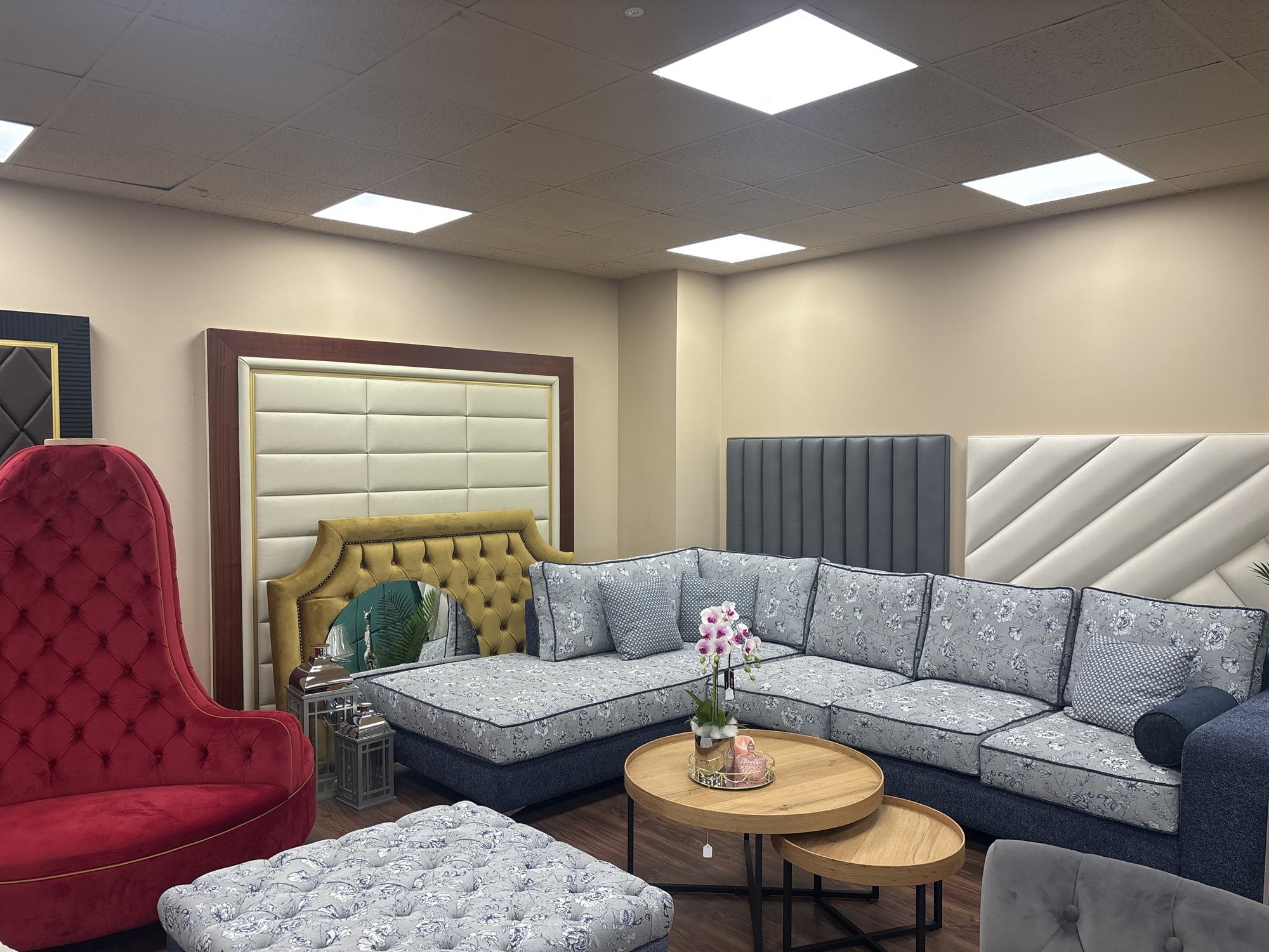 The James Young showroom with a floral corner sofa, tufted velvet chair, headboards and upholstered wall panels